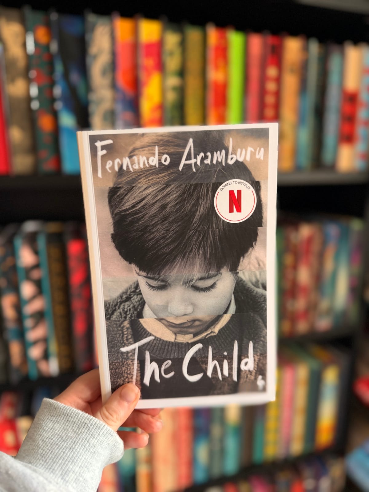 A hand holding a copy of The Child by Fernando Aramburu.